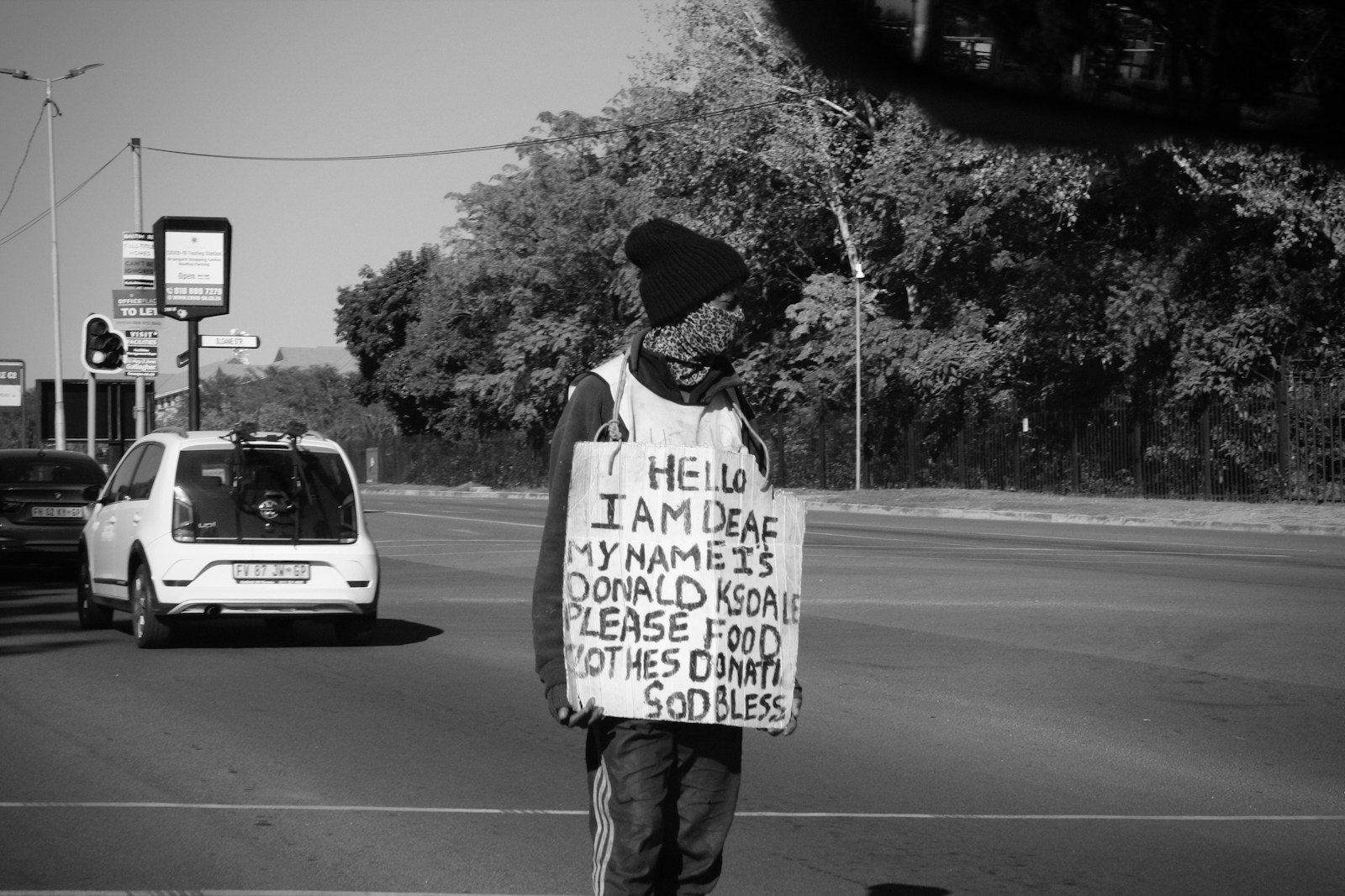 a man holding a sign on the side of the road
